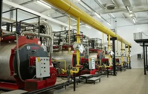 Reihe industrieller Dampfkessel mit gelben Gasleitungen in einer Kesselhalle