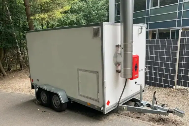 Mobile Heizzentrale auf einem Tandemanhänger mit Abgasrohr neben einem Gebäude